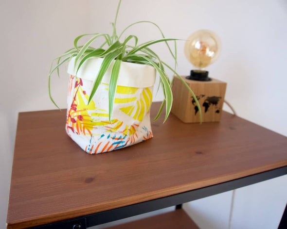 Panière de rangement en tissu utilisée en cache-pot moderne unique colorée tropical sur console avec une lampe